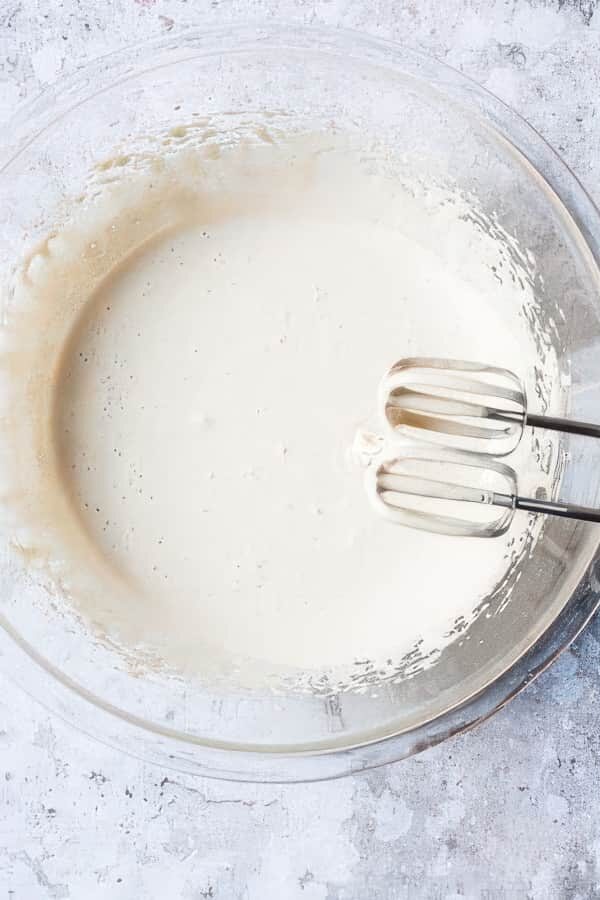 Whisked eggs in bowl with a mixer.