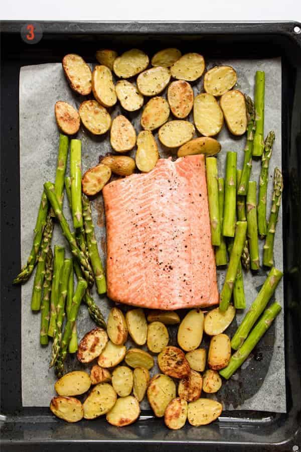 Baked salmon with potatoes and vegetables on a baking tray